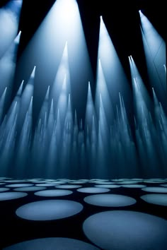 several spotlights are shining down on a stage with circles in the floor and lights behind them