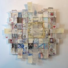 a piece of art made out of old newspaper and other papers on a wall with a gold frame