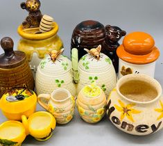 many different vases and jars are sitting on the table together, including one with a bee