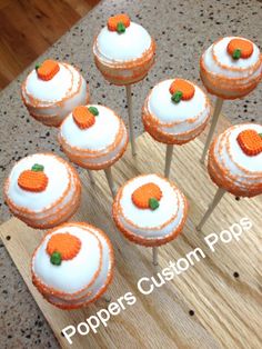 there are many cupcakes with orange decorations on top of each one and the words poppers custom pops above them