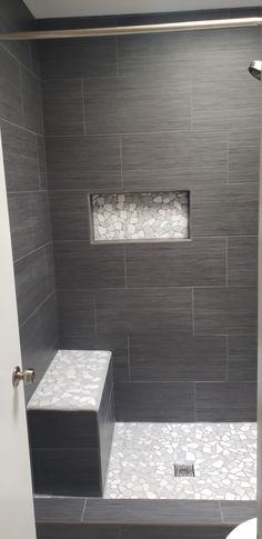 a white toilet sitting next to a walk in shower with gray tile on the walls