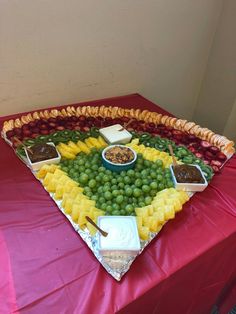 a platter filled with fruit and dips on top of a red table cloth