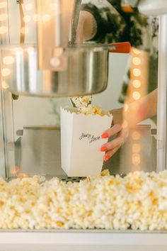 a woman is holding a bag of popcorn in front of a machine with lights on it