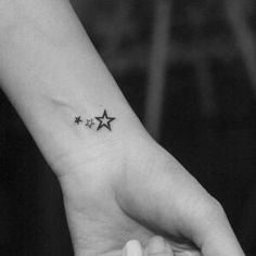 a small star tattoo on the left inner wrist is shown in this black and white photo