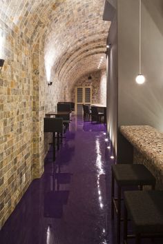 an empty restaurant with purple flooring and stone walls