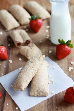 some food is laying out on a wooden table with strawberries and yogurt