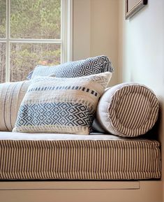 the pillows are stacked on top of each other in front of a window sill