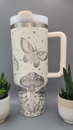 a coffee cup sitting next to some succulents and potted cacti