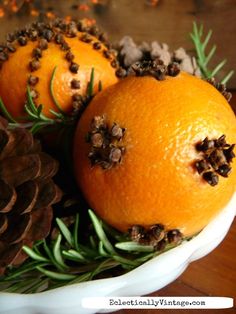 two oranges are sitting in a bowl with pine cones