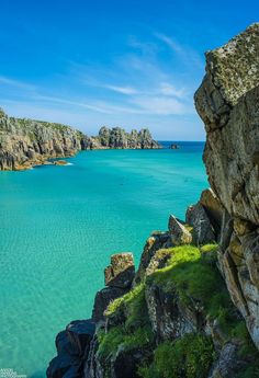 the water is crystal blue and green with rocks on both sides, and cliffs in the background