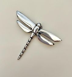 a silver dragonfly brooch sitting on top of a table