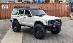 a white jeep parked in front of a shipping container