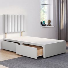 a white bed with two drawers underneath it