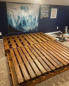 a bed made out of wooden pallets in front of a painting on the wall