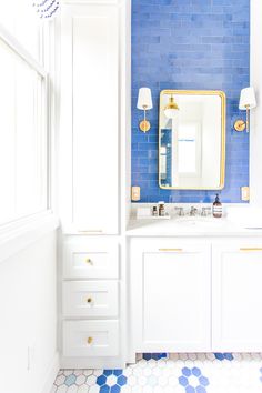 a bathroom with blue and white tiles on the wall, sink and mirror in it