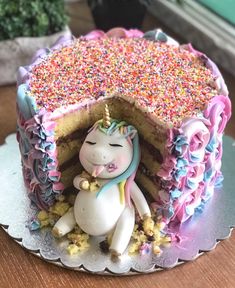 a unicorn cake with sprinkles on it and a slice missing from the cake