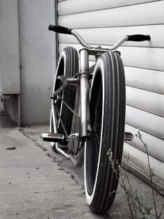 a bicycle parked next to a building on the side of the road in black and white