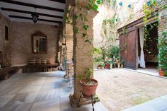 an indoor courtyard with potted plants and benches on the side walk, surrounded by brick walls