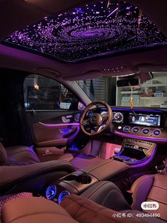 the interior of a luxury car with purple lights and leather seats, along with an entertainment center