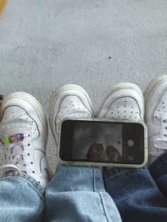 someone taking a photo with their cell phone while sitting on the floor in front of them