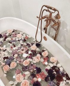 a bathtub filled with lots of flowers next to a faucet