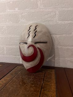 a white mask sitting on top of a wooden table next to a brick wall and floor