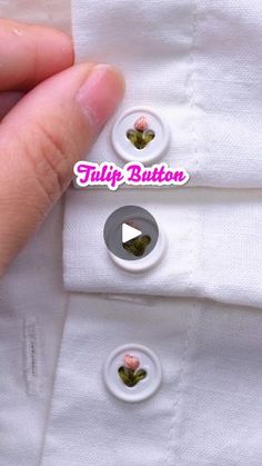 someone is holding their button to show the buttons on his white dress shirt with pink flowers