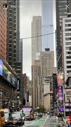 a city street filled with lots of traffic and tall buildings in the background on a cloudy day