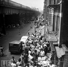 an old black and white photo of people walking down the street