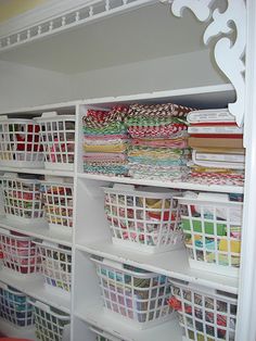 the shelves are filled with baskets and fabrics