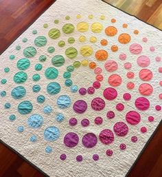 a multicolored polka dot quilt sitting on top of a wooden floor