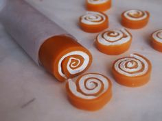 an orange and white candy roll with swirls on it's wrapper next to other candies