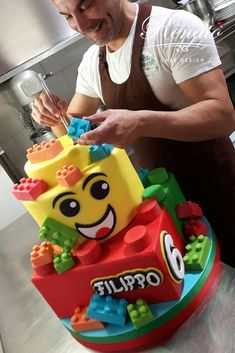 a man cutting into a cake with legos on it