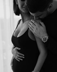 a pregnant woman is hugging her husband's chest