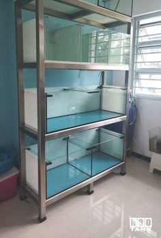 a metal and glass shelving unit in a room with white tile flooring, blue walls and windows