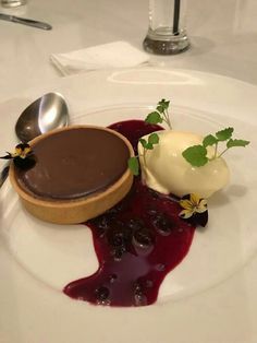 a white plate topped with a dessert covered in chocolate sauce and garnished with green leaves