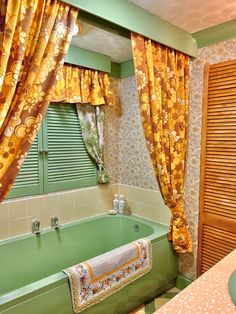 a green bath tub sitting under a window next to a sink and shower curtain in a bathroom