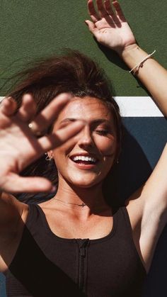 a woman standing on top of a tennis court holding her hands up