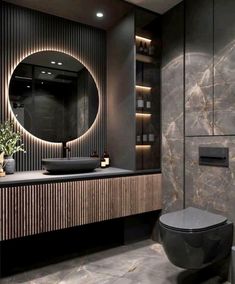 a bathroom with a round mirror and black counter top in front of a marble wall