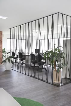 an office area with chairs and plants in the center, surrounded by glass partitions