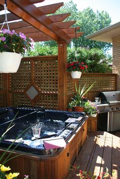 an outdoor hot tub in the middle of a wooden deck with potted plants on it