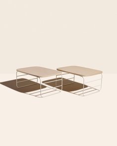 two tables sitting on top of each other in the middle of an empty room with light colored walls