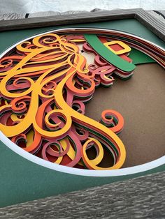 an intricate paper cut out of a woman's head on display in a wooden frame