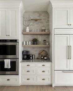 a kitchen with white cabinets and stainless steel stove top oven, built - in shelving