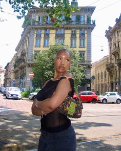 a woman is standing on the street with her arms crossed and looking at the camera