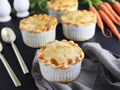 three small pies sitting on top of a table next to carrots