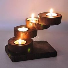 three candles are lit on top of a wooden stand that is made out of wood