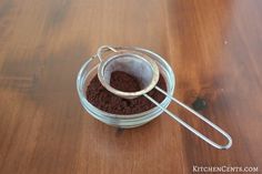 a glass jar filled with dirt sitting on top of a wooden table next to a spoon