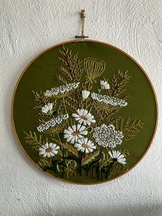 a green wall hanging with white flowers on it