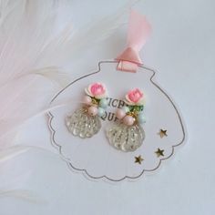 two pink roses and pearls are attached to the back of a pair of earrings